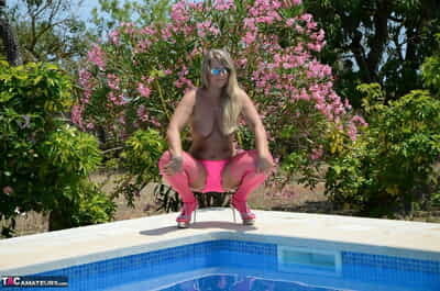 Over 30 blonde Sweet Susi gets naked beside a pool in pink hosiery and shades