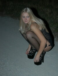 Young blonde Tiffany struts in black lingerie and stockings on a road at night