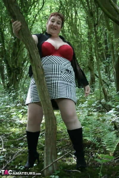 Mature lady Kinky Carol shows her huge tits and butt amid undergrowth