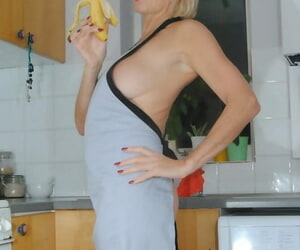 Mature MILF with blonde hair wears only an apron while devouring a banana