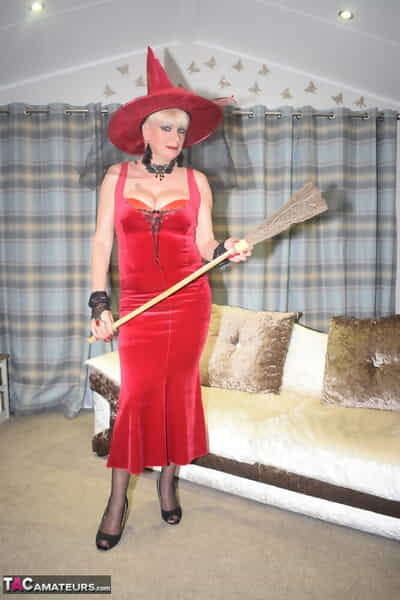 Older blonde removes a red velvet dress pose nude in a witchs hat and hosiery