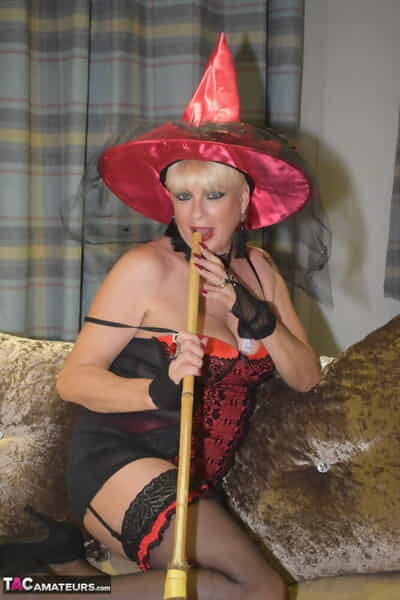 Older blonde removes a red velvet dress pose nude in a witchs hat and hosiery