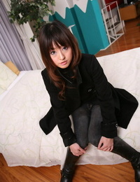 Japanese girl with a pretty face models non in nature\'s garb in a black coat and jeans