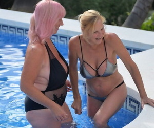 Mature blonde women frolic in a swimming pool with their swimsuits on