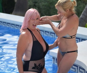 Mature blonde women frolic in a swimming pool with their swimsuits on
