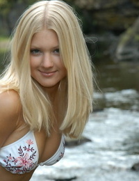 Young blonde girl Tiffany models on rocks in a river wearing a string bikini