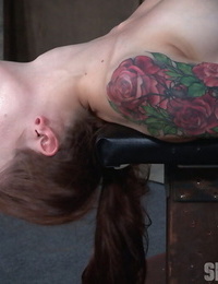 Tattooed female Anna De Ville endures a jaw fuck on a subjugation table