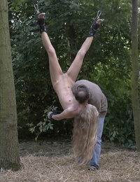 Young blonde girl has her hair pull after being suspended upside down in woods