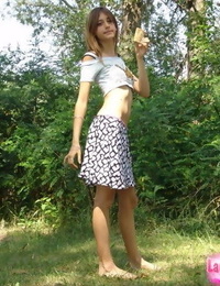 Shapely young youthful in tiny t-shirt and skirt posing outdoors