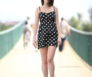 Unassisted woman removes her polka brindled dress while out be incumbent on a walk in focus on