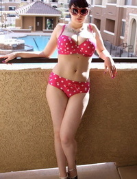 Teen girl Susy Rocks models a polka-dot bikini in shades on a balcony