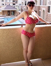 Teen girl Susy Rocks models a polka-dot bikini in shades on a balcony