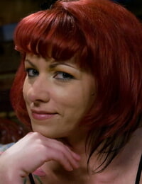 Tattooed redhead Kylie Ireland flashes an upskirt butt cheek on a sofa
