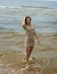 लंबा किशोर मीना लटकी हुई है नम कपड़े करने के लिए सूखी जबकि प्रस्तुत नंगे पर एक समुद्र तट