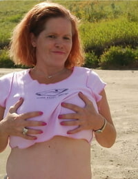 Redheaded amateur Misha covers her big tits in mud while in shallow water