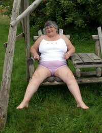 vieux La colombie dame grand-mère libby expose Son seins sur Un arrière-cour banc le balancement