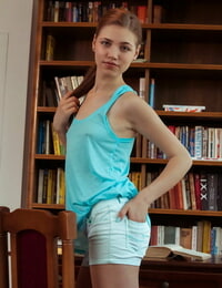 nastolatek solo Dziewczyna Yasmin pauzy jej badania w model Nagie Nagie przed A bookcase