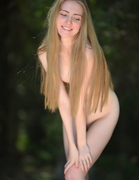 Caucasian teen Lena Flora removes a sexy dress for nude poses on a stump
