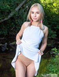 Young looking blonde Maya kneels nude in a stream after spreading her vagina