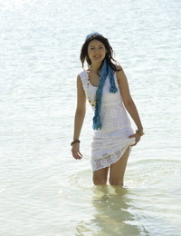 Asian girl deliberate into the ocean to her knees in a white sundress