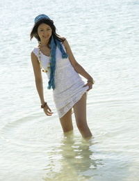 Asian girl wander into the ocean to her knees in a white dress