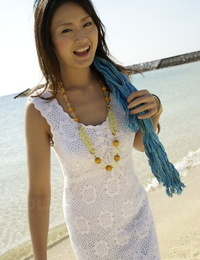 Asiático Chica deliberada en el océano a su de rodillas en Un blanco vestido