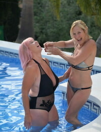 Mature blonde ladies frisky in a swimming pool with their bathing suits on