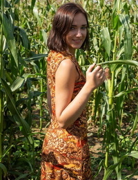 Young dark-haired Oxana Chic attends to her naughty pussy on floor of cornfield