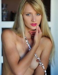 Erotic model Nika N dangles herself over the sofa bare & barefoot in beads