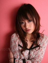 اليابانية نموذج مع A جميلة الوجه تقف الملبس ضد A الوردي الجدار