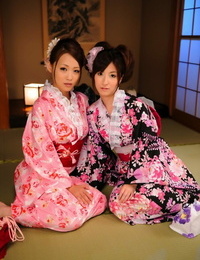 um par de japonês gueixa modelo juntos no seus brilhantemente colorido Kimonos