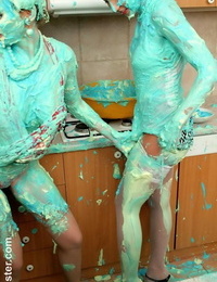 Clothed wailing cover each other in cake mix during a food struggle in kitchen
