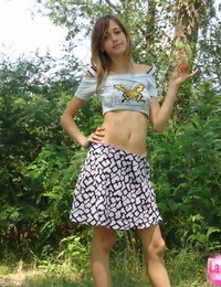 shapely jovem Adolescente no pequeno t camisa e breve minissaia posando ao ar livre